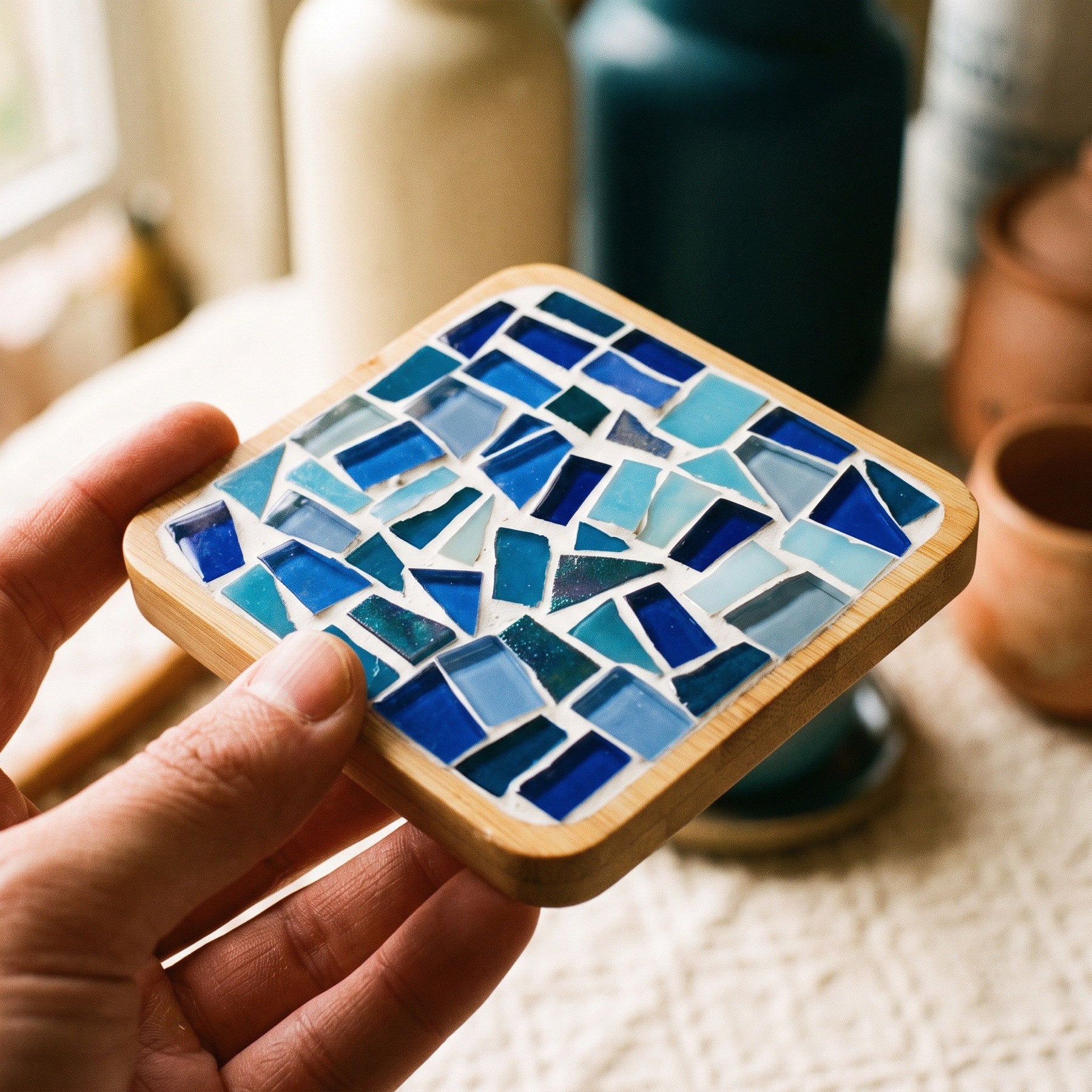 Hands arranging glass tiles in a bamboo base