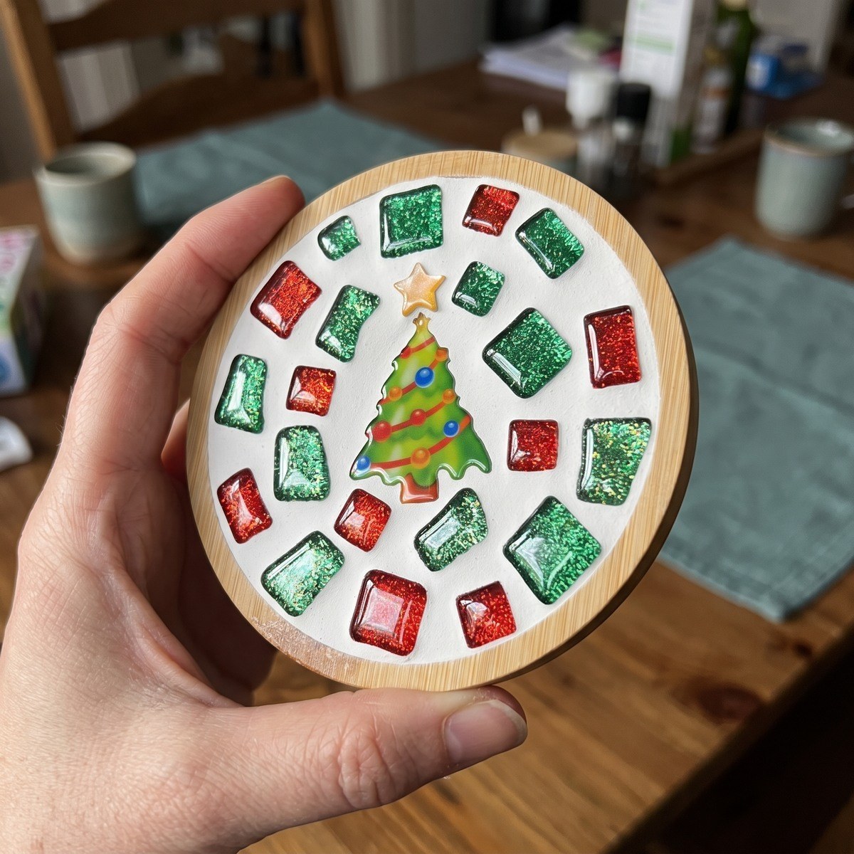 Finished mosaic coaster under a cup on a cabin table